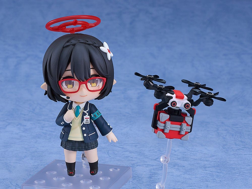 Blue Archive Nendoroid No.2657 Ayane Okusora in a school uniform, with red glasses, dark braided hair with a flower clip, and a red halo accessory, holding a book.