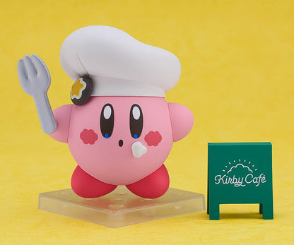 Kirby Nendoroid No.2598 (Cafe Ver.) dressed as a chef, holding a fork, with a green Kirby Café signboard.