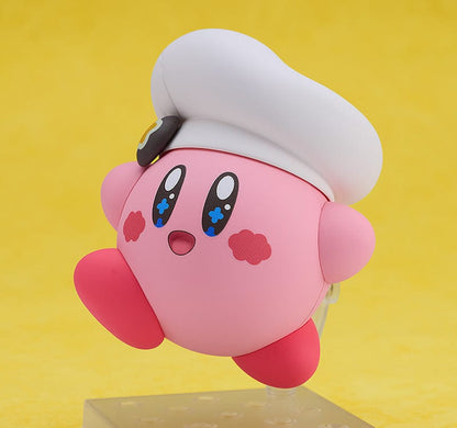 Kirby Nendoroid No.2598 (Cafe Ver.) dressed as a chef, holding a fork, with a green Kirby Café signboard.