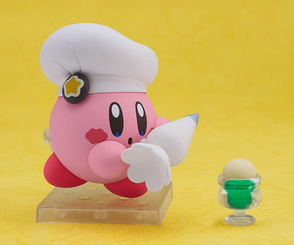 Kirby Nendoroid No.2598 (Cafe Ver.) dressed as a chef, holding a fork, with a green Kirby Café signboard.