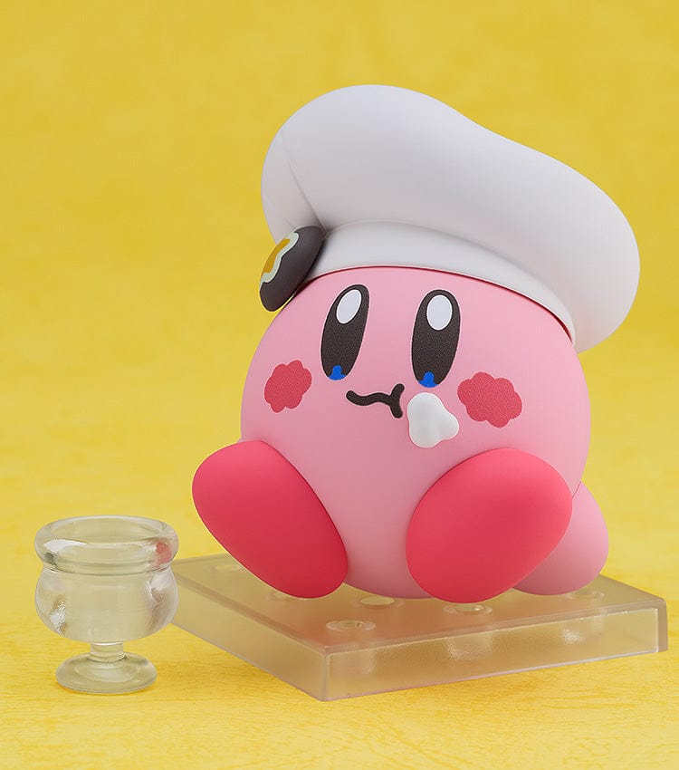 Kirby Nendoroid No.2598 (Cafe Ver.) dressed as a chef, holding a fork, with a green Kirby Café signboard.