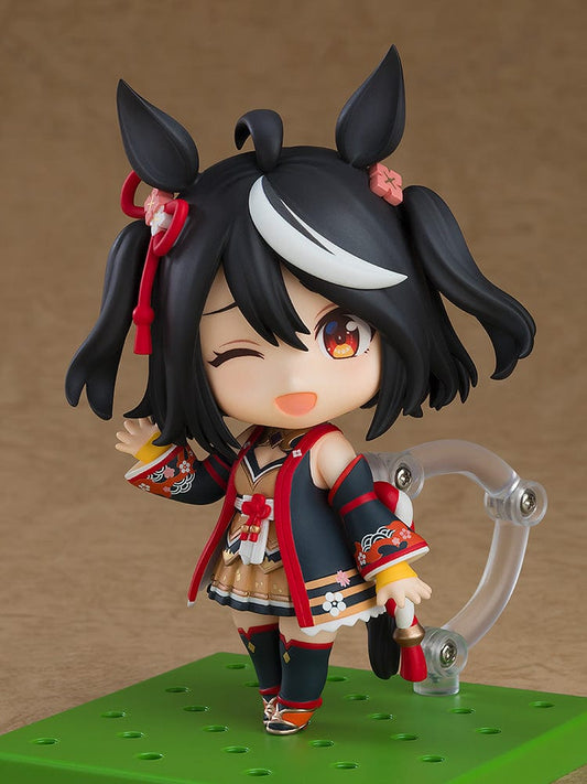 The 'Uma Musume: Pretty Derby Nendoroid No.2468 Kitasan Black' showcases the character in her racing-themed outfit with dynamic black hair decorated with floral accents and dual ponytails, complete with a joyful expression. The figure is set against a simple background, emphasizing its vibrant color scheme and playful design.