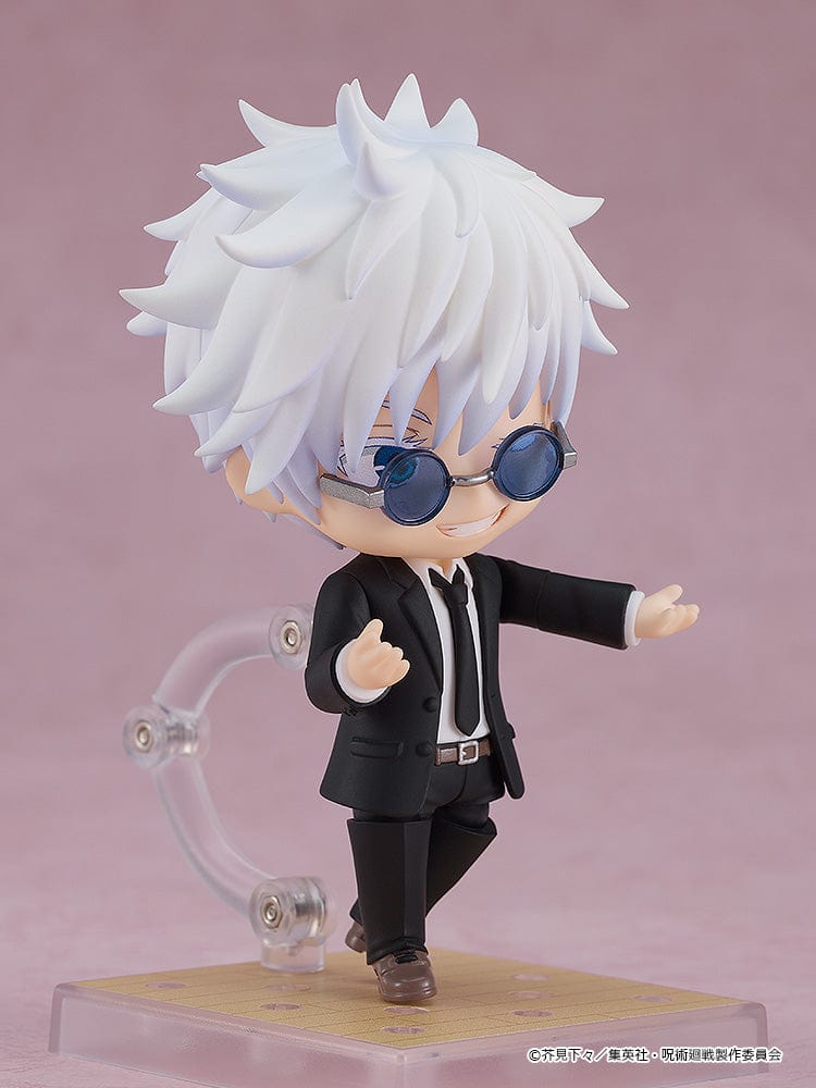 The image shows a Nendoroid of Satoru Gojo from "Jujutsu Kaisen" dressed in a suit. He's striking a confident pose with sunglasses and a scroll stand accessory.