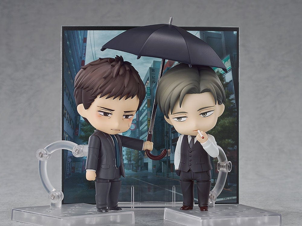 Twittering Birds Never Fly Nendoroid set featuring Yashiro and Chikara Domeki figures. Domeki holds an umbrella over Yashiro, both dressed in formal attire with a city background.