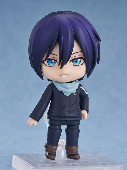 Noragami Nendoroid No.2565 Yato in his iconic dark tracksuit with blue scarf, smiling confidently.