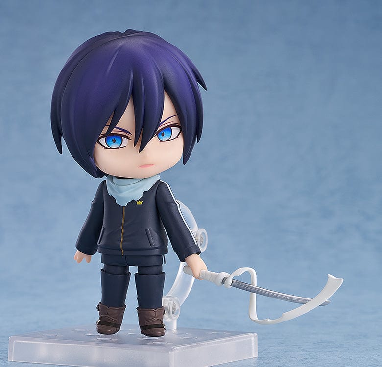 Noragami Nendoroid No.2565 Yato in his iconic dark tracksuit with blue scarf, smiling confidently.