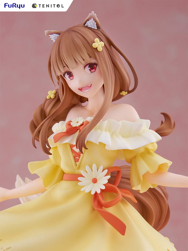 Spice and Wolf Tenitol Holo figure, featuring Holo in a joyful pose wearing a flowing yellow dress with wolf ears and tail, standing on a decorative base.