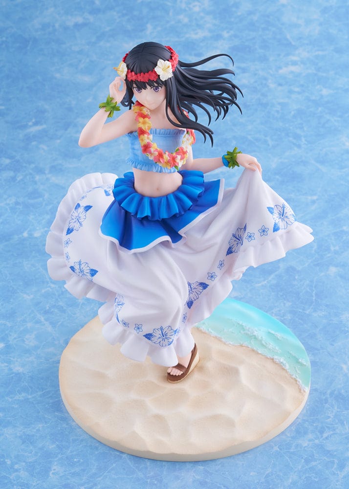 A 1/7 scale figure of Takina Inoue from "Lycoris Recoil" in a Hawaiian version ensemble, with long black hair and a peaceful expression. She is adorned with a floral lei and hairpiece, wearing a blue ruffled top and a white skirt with blue floral prints. The dynamic pose captures her mid-dance, with her skirt lifted to reveal a layered blue underskirt, standing on a sandy beach base with a hint of ocean wave.