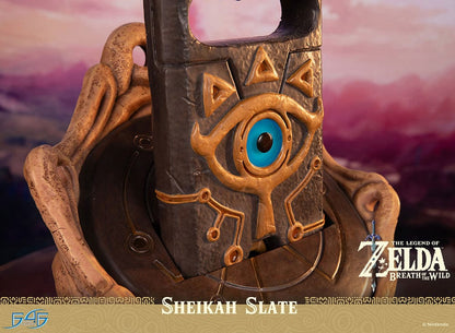 Statue of the Sheikah Slate from 'The Legend of Zelda: Breath of the Wild', with detailed carvings and symbols, against a scenic Hyrule background, part of a limited edition collectible set.