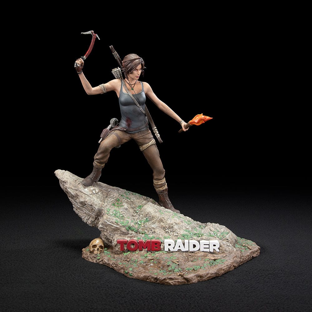 Tomb Raider Lara Croft (Survivor Era) Statue holding climbing axe and torch, in rugged survival gear on rocky base with foliage and skull